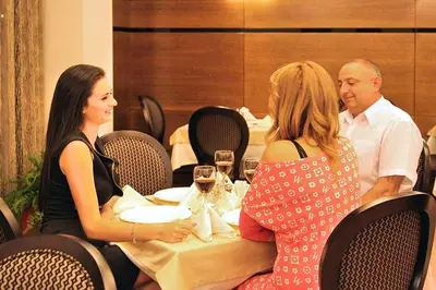a group of people sitting around a table in a restaurant at Aqua Viva Spa Hotel in Velingrad