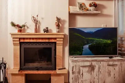 a living room with a fireplace and a flat screen tv at Lake View Apartment in Pamporovo