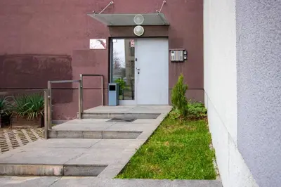 a building with a white door and some grass at Fantastic Studio Studentski Grad in Sofia