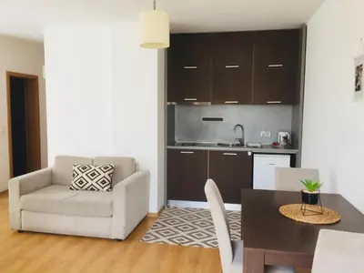 a living room with a table and a chair and a kitchen at Fantastic Studio Studentski Grad in Sofia