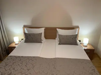 a large white bed with two pillows and two lamps at Apartment City Park Sandanski in Sandanski