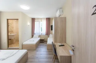 a hotel room with two beds and a desk at Къща за гости Перуника in Sapareva Banya