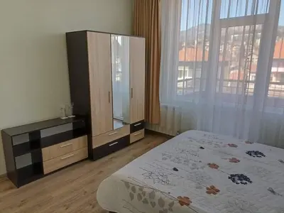 a bedroom with a bed and a dresser and a large window at Приятелската къща in Velingrad