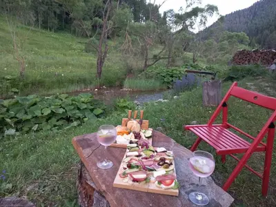 a table with a plate of food and two glasses of wine at Къща край реката - Триград in Trigrad