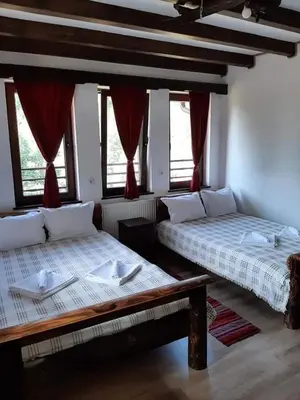 two beds in a room with red curtains at Къща за гости 