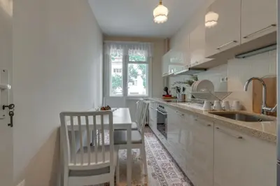 a kitchen with white cabinets and a sink and a table at Beautiful Jewel in Top Center in Sofia