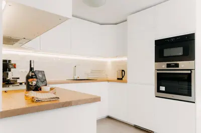 a white kitchen with white cabinets and black appliances at Magnificent apartment in the mountains in Banite