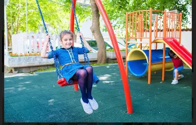 a little girl sitting on a swing in a playground at Hotel Shterev Sopot in Sopot