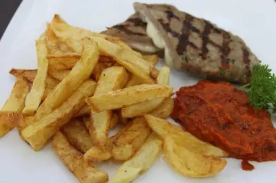 a plate of food with french fries and meat at Hotel Shterev Sopot in Sopot