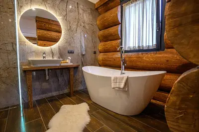 a bathroom with a tub and a sink and a mirror at Alpina Luxury Chalets in Banya