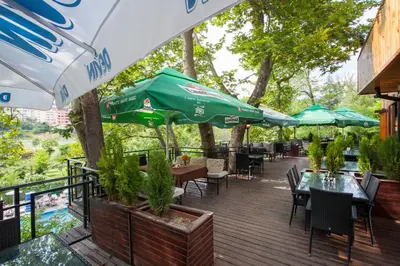a wooden deck with tables and chairs and umbrellas at Бунгала Сън Сити in Sandanski