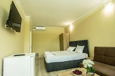 a room with a bed and a couch and a tv at Бунгала Сън Сити in Sandanski