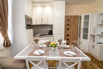 a white kitchen with a white table and chairs at Park Apartment Emilin in Sandanski