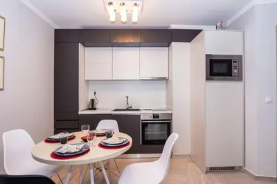 a kitchen with a table and white chairs in a room at Elegance, City center, Kapana in Plovdiv