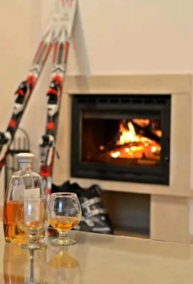two glasses of wine on a table in front of a fireplace at Private Apartment in Grand Monastery in Pamporovo