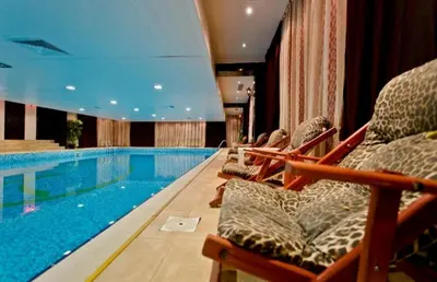 a swimming pool in a hotel with chairs next to it at Private Apartment in Grand Monastery in Pamporovo