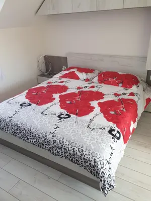 a bedroom with a bed with red flowers on it at Cosy Charming Apartment in Blagoevgrad
