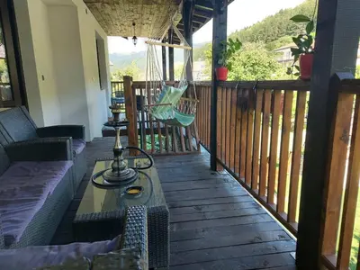 a porch with a swing and a hammock on a deck at GREEN HOUSE - Попниколови in Sapareva Banya
