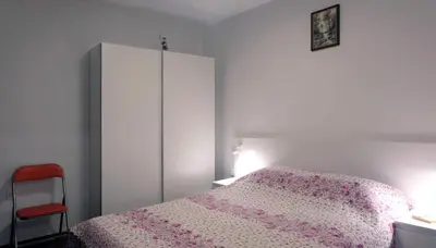 a bedroom with a bed and a cabinet and a chair at Апартамент Перла in Sandanski