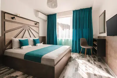 a bedroom with a large bed with blue curtains and a chair at ОРФЕЕВИТЕ ПЕСНИ in Devin