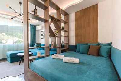 a bedroom with a blue bed with two pillows on it at ОРФЕЕВИТЕ ПЕСНИ in Devin