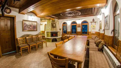a dining room with a table and chairs and a fireplace at Къща за гости Черна река in Ribarica