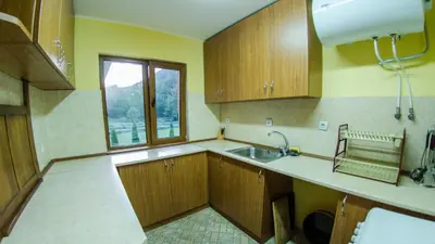 a kitchen with wooden cabinets and a sink and a window at Къща за гости Черна река in Ribarica