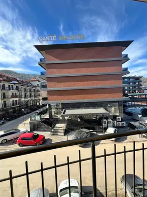 a large building with cars parked in a parking lot at Vega Apartment in Velingrad