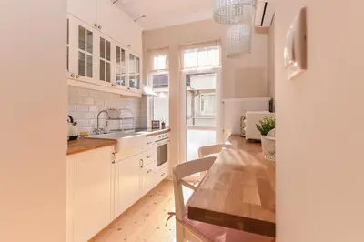 a kitchen with white cabinets and a wooden table at Chez Marie - Cozy One-Bedroom with Balcony by Flat Mаnager in Sofia