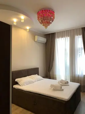 a bedroom with a large bed with a chandelier at CENTER APARTMENT PLOVDIV in Plovdiv