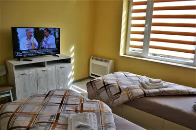 a bedroom with a bed and a flat screen tv at Guest Apartment Balkan in Karlovo