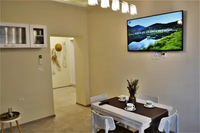 a dining room with a table and a tv on the wall at Guest Apartment Balkan in Karlovo