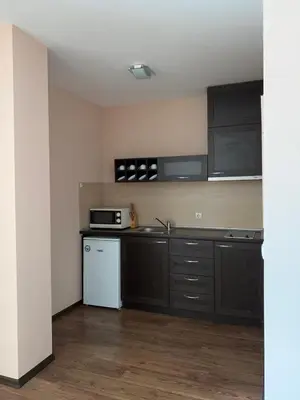 a kitchen with black cabinets and a white refrigerator at Апартамент в комплекс Bansko Royal Towers in Bansko