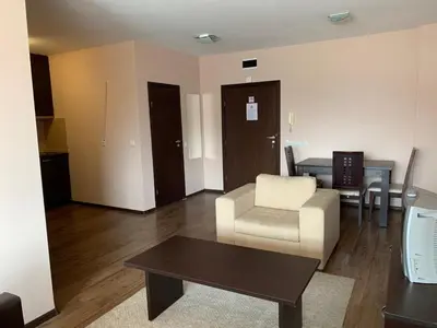 a living room with a couch and a chair and a table at Апартамент в комплекс Bansko Royal Towers in Bansko