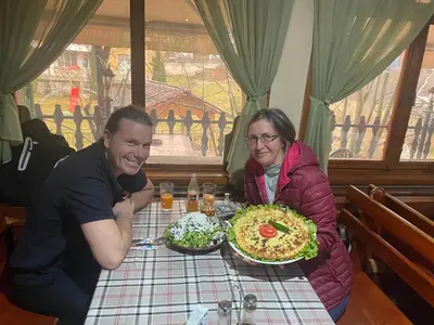 a man and woman sitting at a table with a pizza at Къща за гости Динас in Zmeitsa