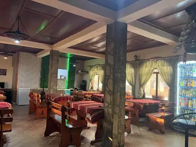 a restaurant with wooden tables and chairs and green lights at Къща за гости Динас in Zmeitsa