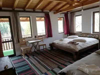 a bedroom with two beds and a table and windows at GUEST HOUSE ELENA in Kosovo
