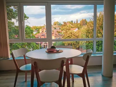 a table and chairs in a room with a large window at So Close Kapana - 2 Rooms Central Apartments in Plovdiv