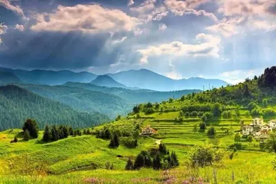 a green hillside with a small town in the distance at Stoykite-Pamporovo Nature Retreat in Stoykite