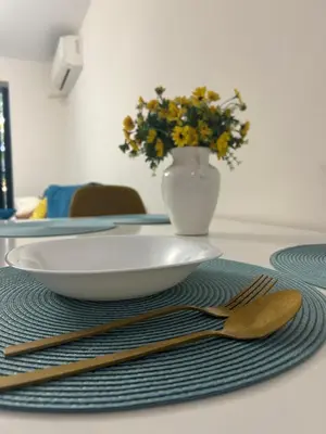 a table with a plate and fork and a vase with flowers at Sandanski Apartments Top Center in Sandanski