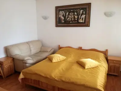 a bedroom with a yellow bed and a couch at Вила Хоризонт in Tsigov Chark