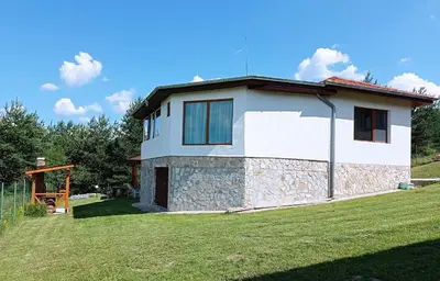 a small white house with a grass yard at Вила Хоризонт in Tsigov Chark