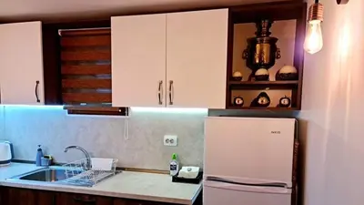 a kitchen with white cabinets and a sink and a refrigerator at ПАУНОВАТА КЪЩА in Yasă-Koriya