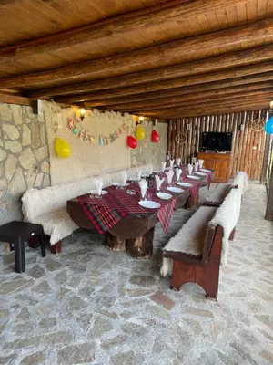 a dining room with tables and couches in a building at ПАУНОВАТА КЪЩА in Yasă-Koriya