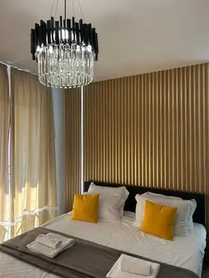 a bedroom with a bed with yellow pillows and a chandelier at Sandanski Apartments Park Center in Sandanski