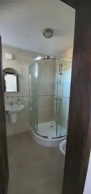 a bathroom with a glass shower and a toilet at Guest House Ela in Dolna Banya