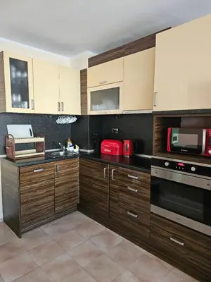 a kitchen with wooden cabinets and a microwave at Apartment Lozenets in Sofia