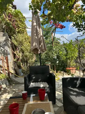 a patio with an umbrella and a chair and a table at Didi Park House къща с две спални in Sandanski