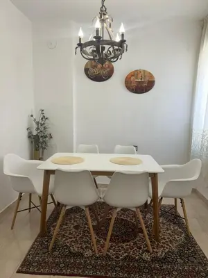 a dining room table with white chairs and a chandelier at Didi Park House къща с две спални in Sandanski
