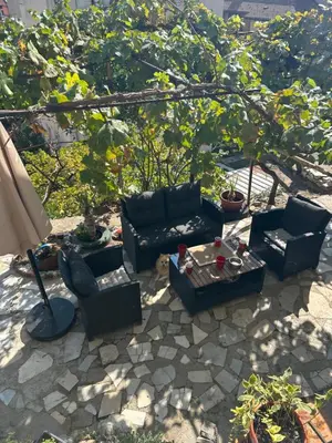 a patio with couches and a table and an umbrella at Didi Park House къща с две спални in Sandanski